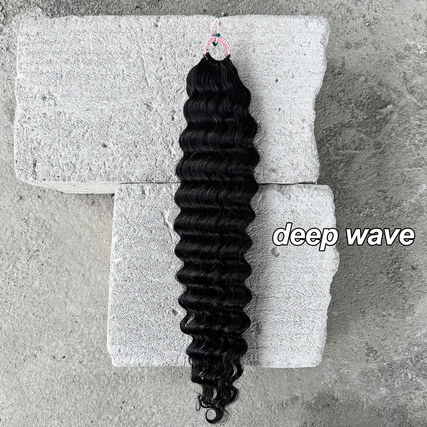 Deep wave black hair extension bundle on concrete blocks, curly hair texture highlighted.