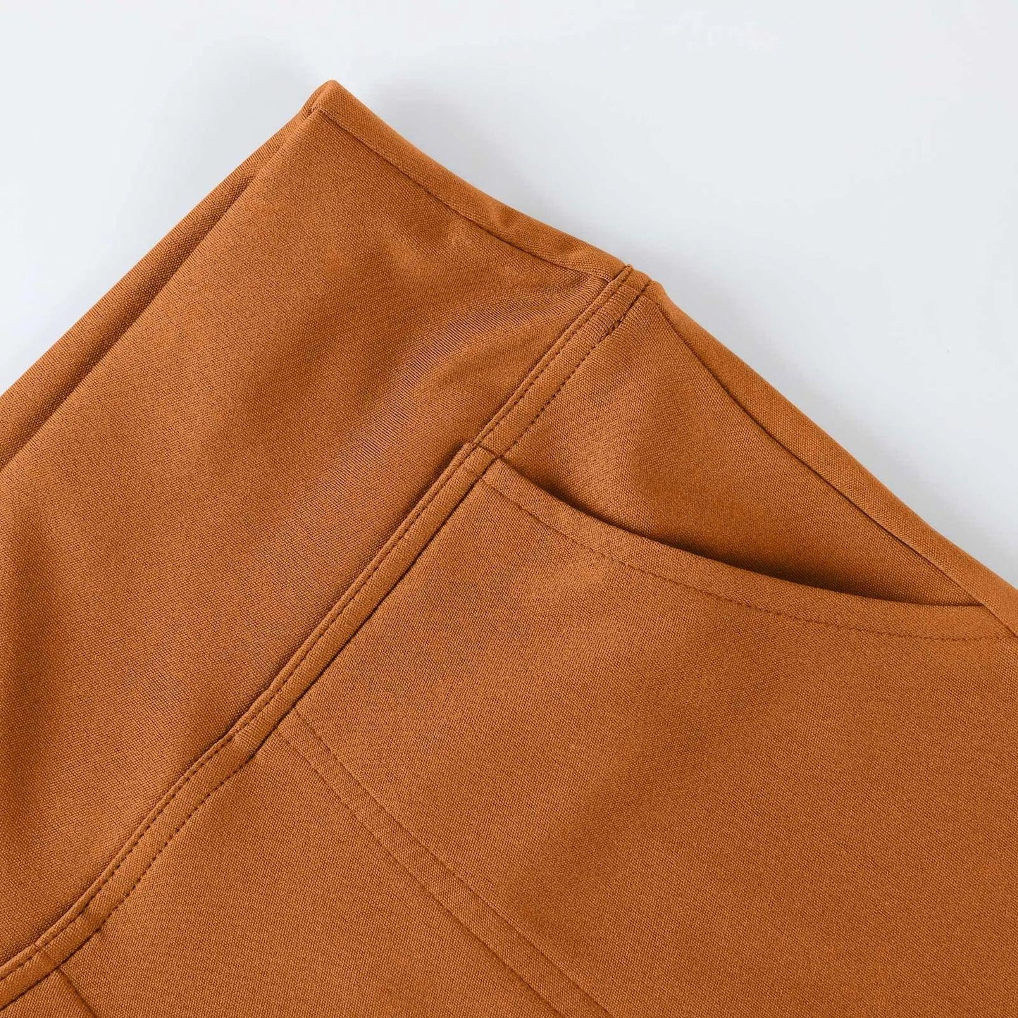 Close-up of brown fabric pants pocket with visible stitching on a flat surface.