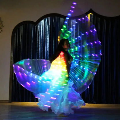 Dancer performing with LED light up wings, rainbow colors glowing in dark indoor setting