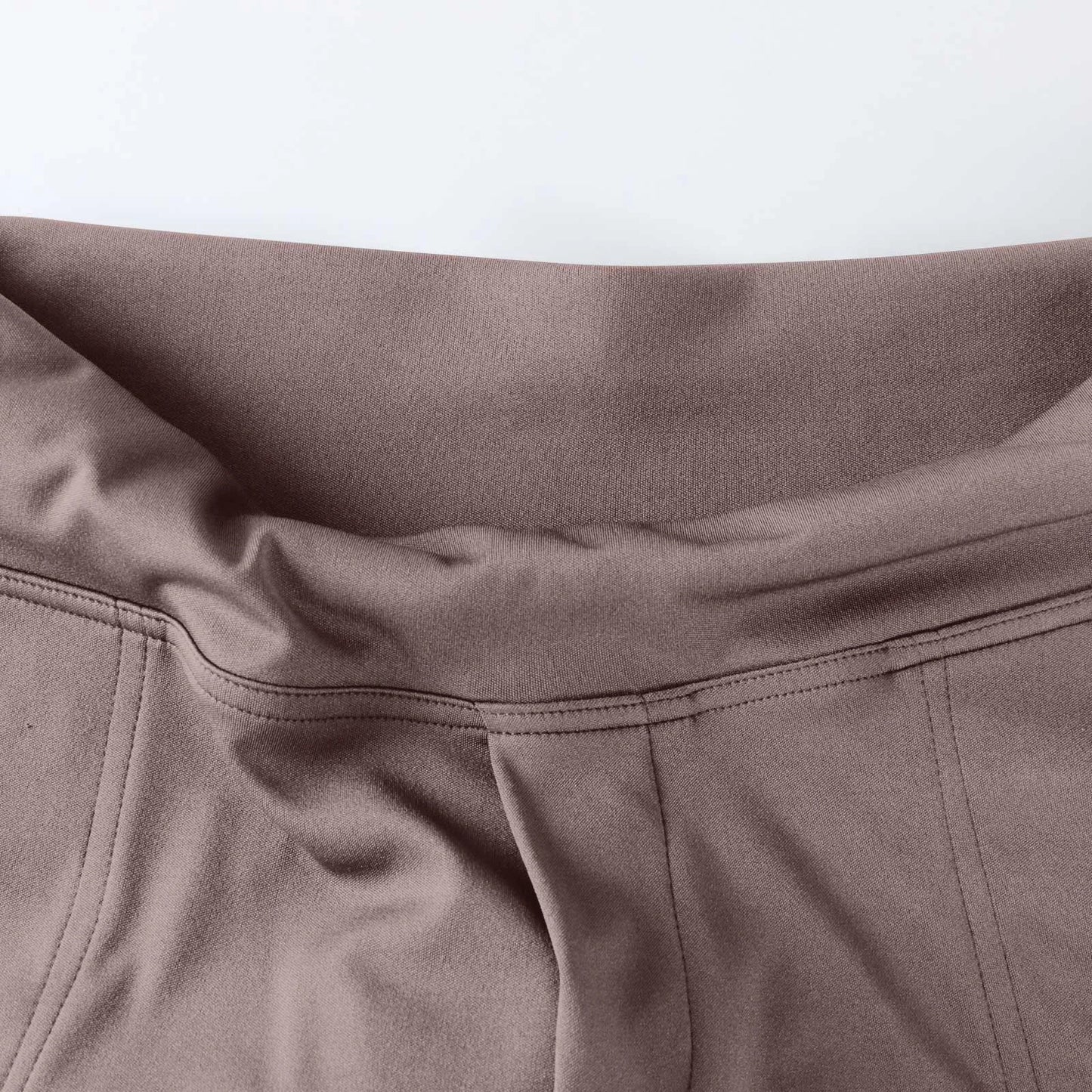 Close-up of high-waisted taupe leggings with smooth fabric and visible seams.