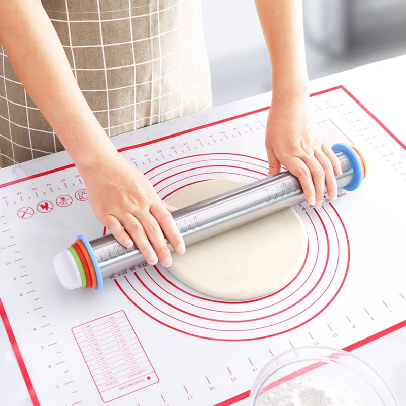 Adjustable stainless steel rolling pin flattening dough on a non-slip baking mat