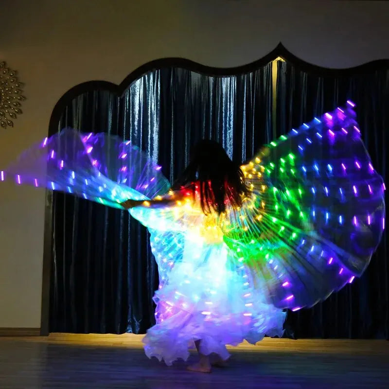 Person dancing with large LED light up wings in a dark room, colorful glowing costume