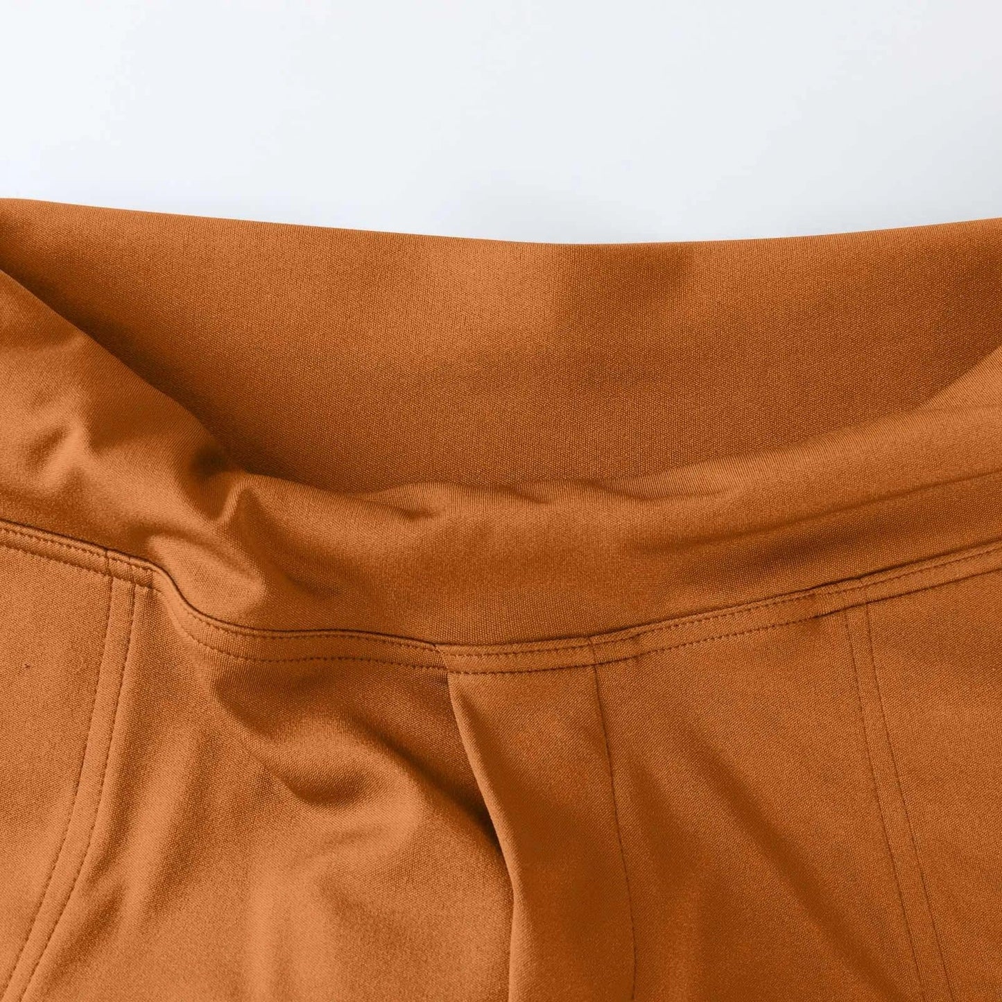Close-up of high-waisted brown pants with smooth fabric and visible stitching detail