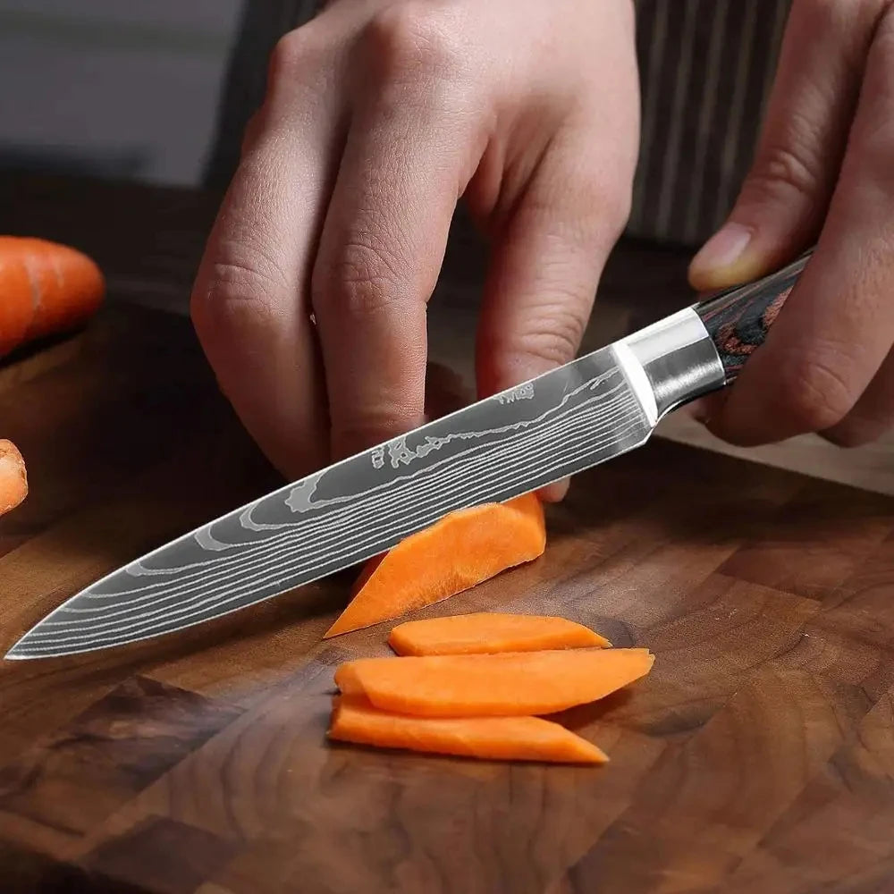Close-up of a hand slicing carrot with a Damascus steel chef knife on a wooden cutting board