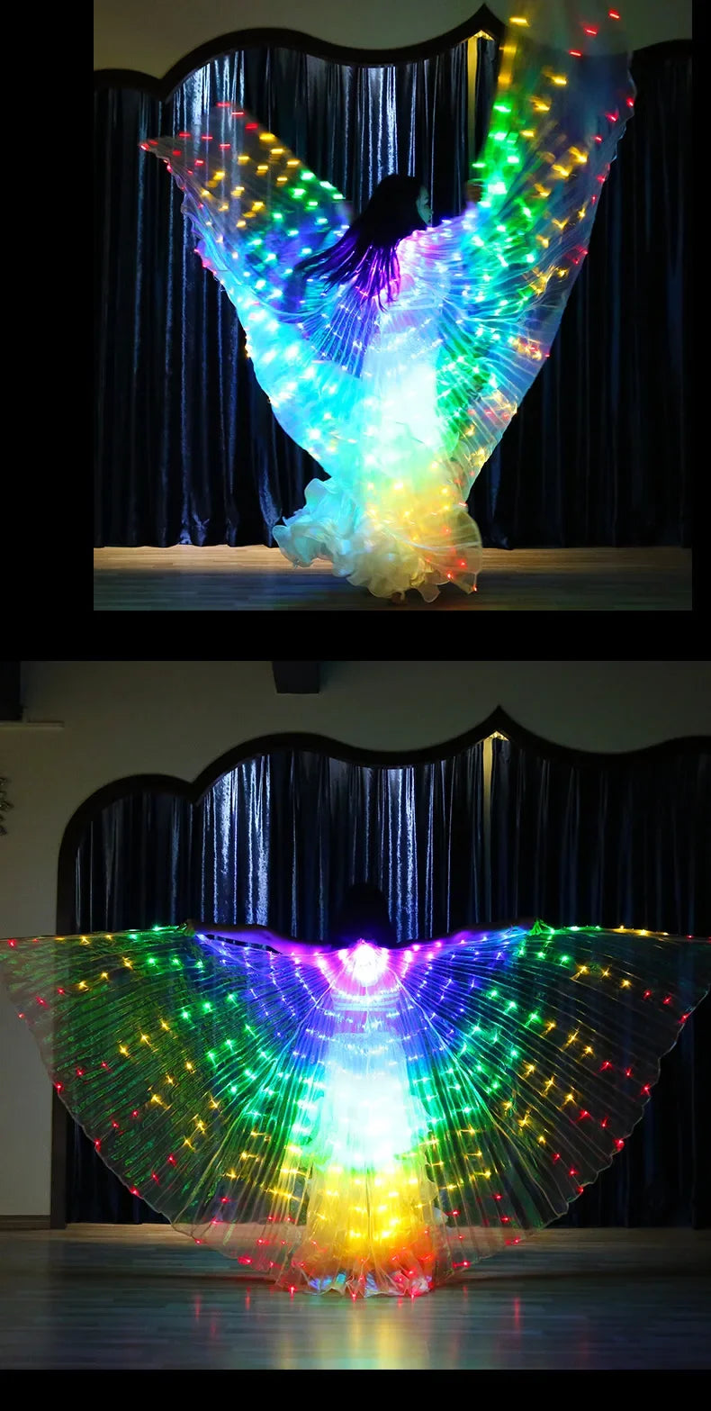 Dancer performing with large illuminated rainbow LED wings on stage, glowing in the dark.