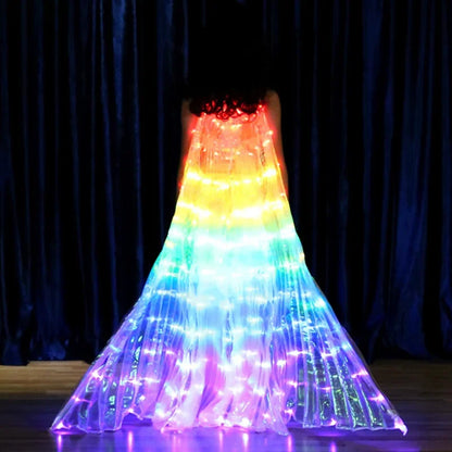 Woman wearing a glowing LED fiber optic rainbow dress on stage with dark curtain backdrop