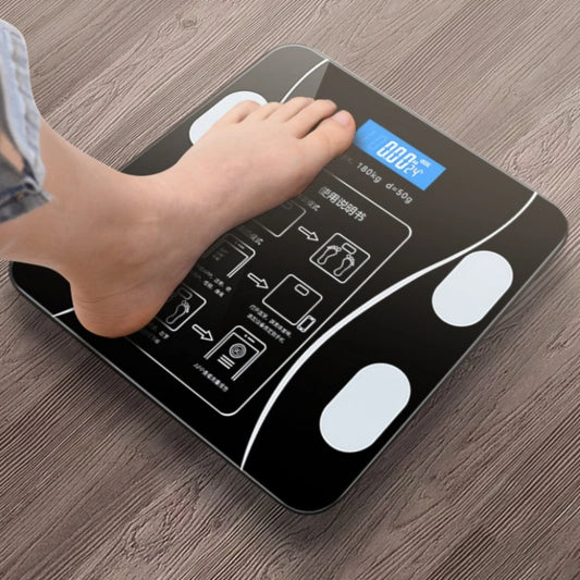 Digital bathroom scale with LCD display and foot stepping on it, placed on wooden floor