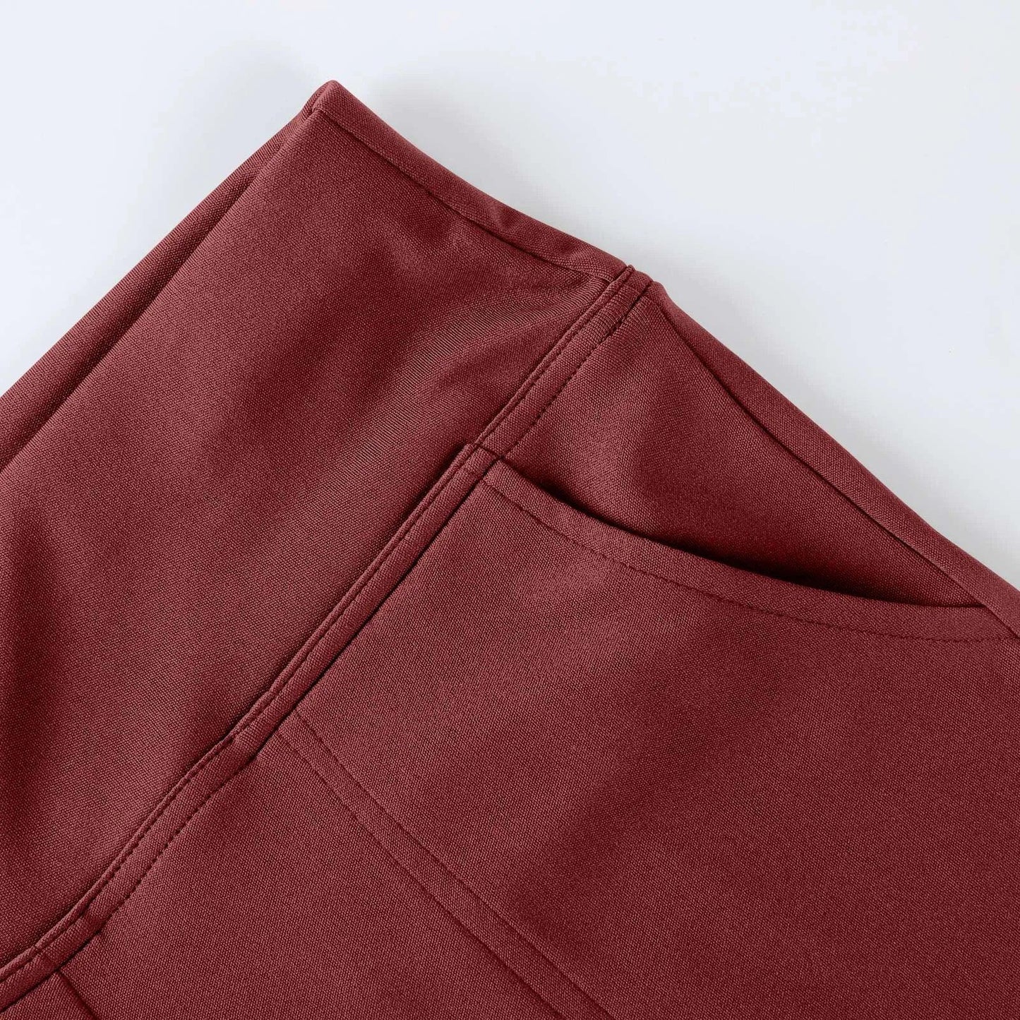 Close-up of maroon athletic leggings with pocket and stitched detail on white background